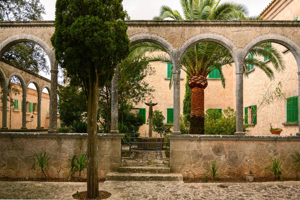 The courtyard of the Santuari de Nostra Senyora de Cura on Randa Monastery Hill is idyllically landscaped with palm trees and figures, Mallorca, Spain - © James Camel / franks-travelbox
